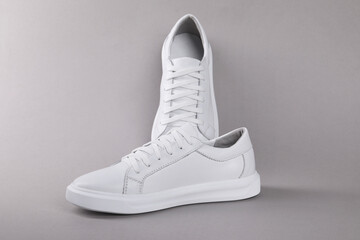 Pair of stylish white sneakers on grey background