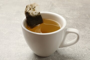Taking tea bag out of cup with at light table, closeup