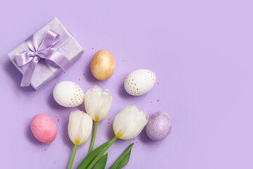 Fototapeta na wymiar Beautiful tulip flowers with painted Easter eggs and gift box on purple background