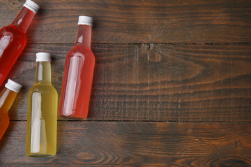 Delicious kombucha in glass bottles on wooden table, flat lay. Space for text