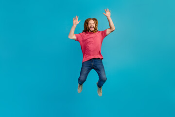 Full body portrait of astonished active person jumping raise arms empty space isolated on blue color background