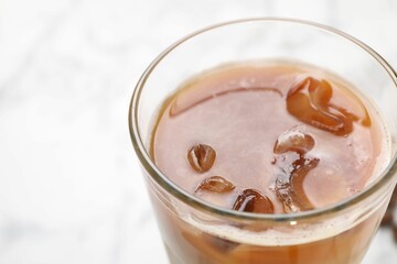 Refreshing iced coffee with milk in glass on white background, closeup. Space for text