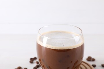 Refreshing iced coffee with milk in glass on white background, closeup