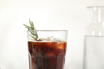 Refreshing iced coffee with rosemary in glass on white background, closeup