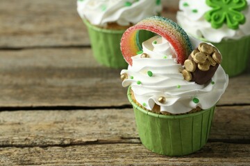 St. Patrick's day party. Tasty festively decorated cupcakes on wooden table, closeup. Space for text