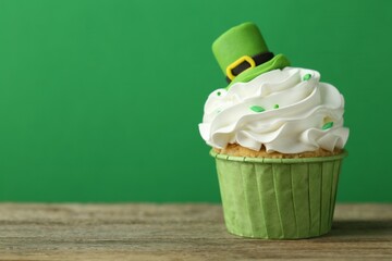 St. Patrick's day party. Tasty cupcake with leprechaun hat topper on wooden table, closeup. Space...