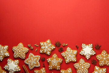 Fototapeta na wymiar Tasty star shaped Christmas cookies with icing and spices on red background, flat lay. Space for text