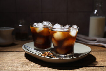 Refreshing iced coffee in glasses, ingredients and spoon on wooden table