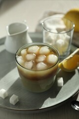 Refreshing iced coffee with milk in glass, sugar cubes and spoon on table, closeup