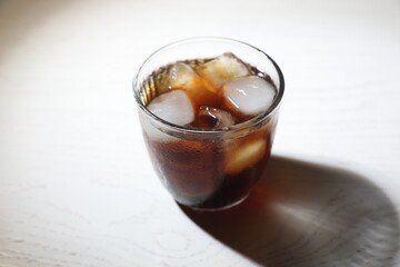 Refreshing iced coffee in glass on white wooden table
