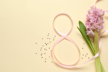 8th of March greeting card design with pink ribbon, beautiful flowers and space for text on beige background, flat lay. International Women's day