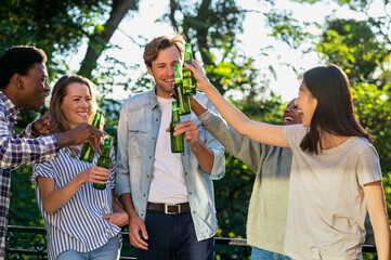 Group of friends toasting with beer bottles standing outdoors