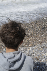 Fototapeta premium Rear view of young person's head looking at seaside waves in Normandie