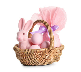 Wicker basket with painted Easter eggs, gift bag and toy bunny on white background
