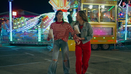Obraz premium Best friends having fun together at illuminated luna park. Happy girls walking