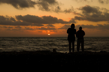 Due persone osservano il tramonto a Marina di Ragusa