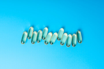 Omega 3 gelatin ampoules lying in a row on a blue background