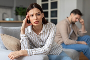 Worried young woman with upset man in background