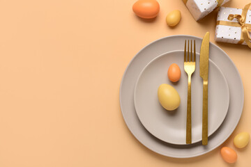 Beautiful Easter table setting with gifts and eggs on orange background