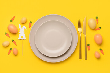 Beautiful Easter table setting served with eggs, toys and bunnies on yellow background