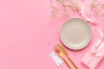 Festive Easter table setting decorated with gifts and eggs on pink background