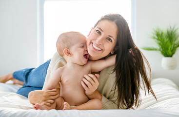 young beautiful mother with a baby boy on the bed at home