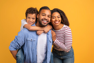 Smiling black family with preteen son embracing in warm group hug