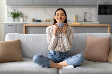 Content young woman enjoying coffee on couch