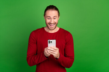 Photo of overjoyed man with stubble long hairdo dressed red pullover look at smartphone read email...