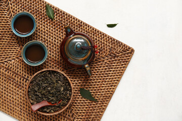 Mat with teapot and cups of puer tea on white background