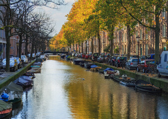 Fototapeta na wymiar Famous Amsterdam city center canal with dutch brick buildings, trees , reflections and anchored boats in sunny autumn day. Netherlands