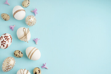 Composition with decorated Easter eggs and purple flowers on blue background