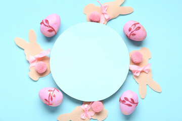 Easter eggs, paper bunnies and blank card on blue background. Closeup