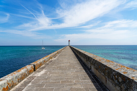 &Agrave; l'extr&eacute;mit&eacute; du m&ocirc;le, le phare du Raoulic se dresse en perspective, t&eacute;moin solennel de la rencontre entre terre et mer &agrave; Audierne, en Bretagne.