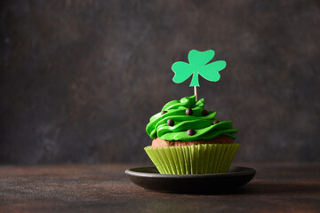 St. Patrick's Day cupcake with green whipped cream decorated clover on dark brown background. Copy...