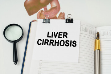 On the table there is a magnifying glass and a notepad with the inscription - Liver cirrhosis