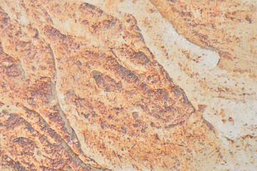 Irregular surface texture of chipped stone with orange tones
