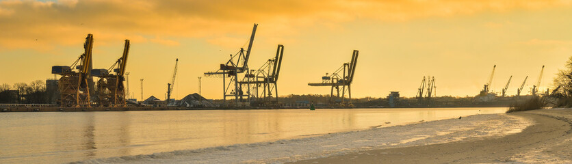 Dźwigi portowe w świetle zachodzącego słońca nad kanałem