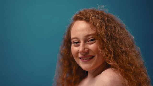 Young pretty redhead plus size or plump woman celebrating her natural body. Positive beautiful female model in white underwear against blue background. Lifestyle portrait with minimal makeup