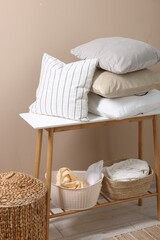 Fototapeta na wymiar Soft pillows and laundry baskets near beige wall indoors