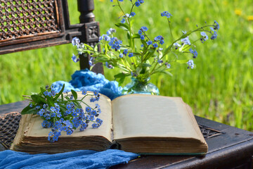 An open antique book on a chair in the garden and flowers, background