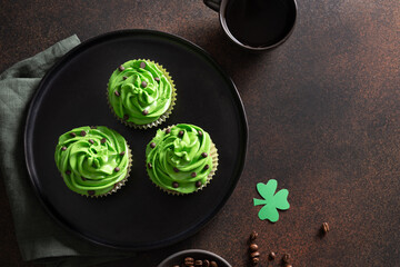 Three chocolate cupcakes with coffee and chocolate sprinkles on brown background. St. Patrick's...