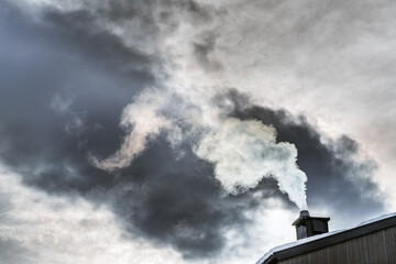 A dramatic scene of white smoke billowing from a chimney against a backdrop of dark, ominous clouds, illustrating concepts like pollution, climate change, or industrial impact