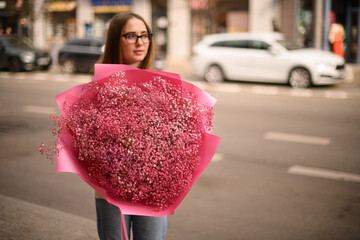 Selective focus on huge bouquet of rustic gypsophila flowers in pink color girl florist holding in...