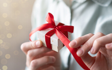 Close-up of a woman wrapping gifts and tying a beautiful pastel ribbon bow