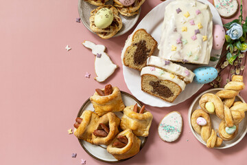 Happy Easter holiday food baking puff pastry and cupcake with Easter Bunny on pastel pink background. Easter breakfast or brunch on a festive table. View from above.