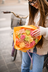 Naklejka premium Young woman holding big and beautiful bunch of fresh carnation flowers in different colors,