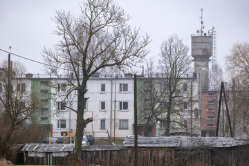old damaged multiapartment building in Latvia countryside. Aged walls and window frames, metal chimneys, satellite dishes, soviet leftovers. Shelter for poor people