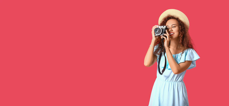 Beautiful young woman with photo camera on pink background with space for text