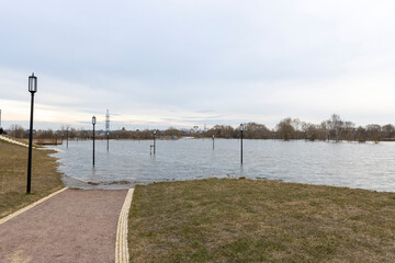 flooded park with paths and sidewalks, early spring flood, river overflowing its banks,...